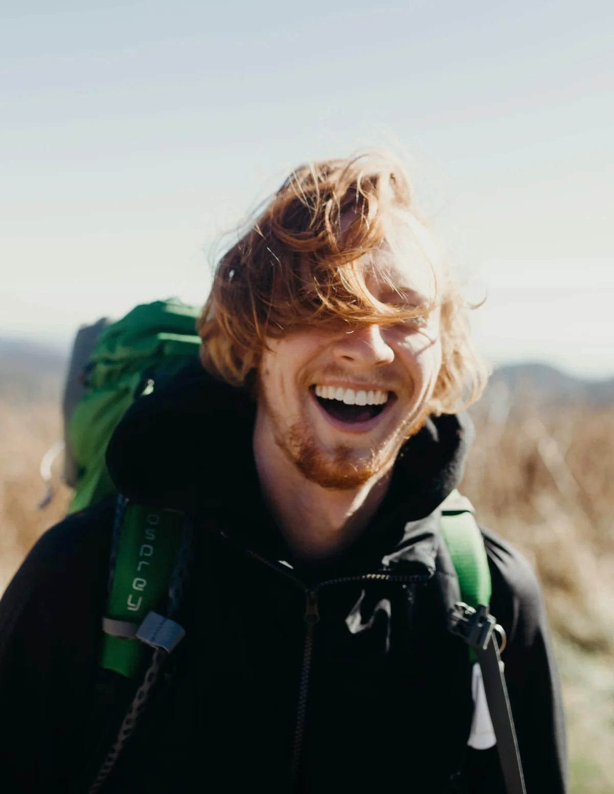 Man with a backpack laughing outdoors. Image credit: Mike baker