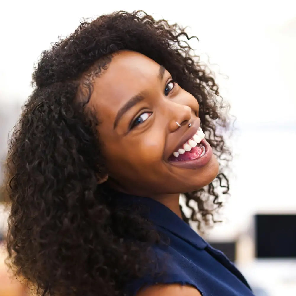 Woman with curly hair smiling against a blurred background. Image credit: Isaiah McClean