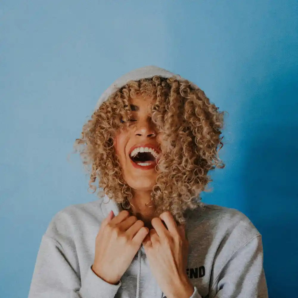 Happy woman wearing hoodie and laughing with background. Image credit Ivana Cajina