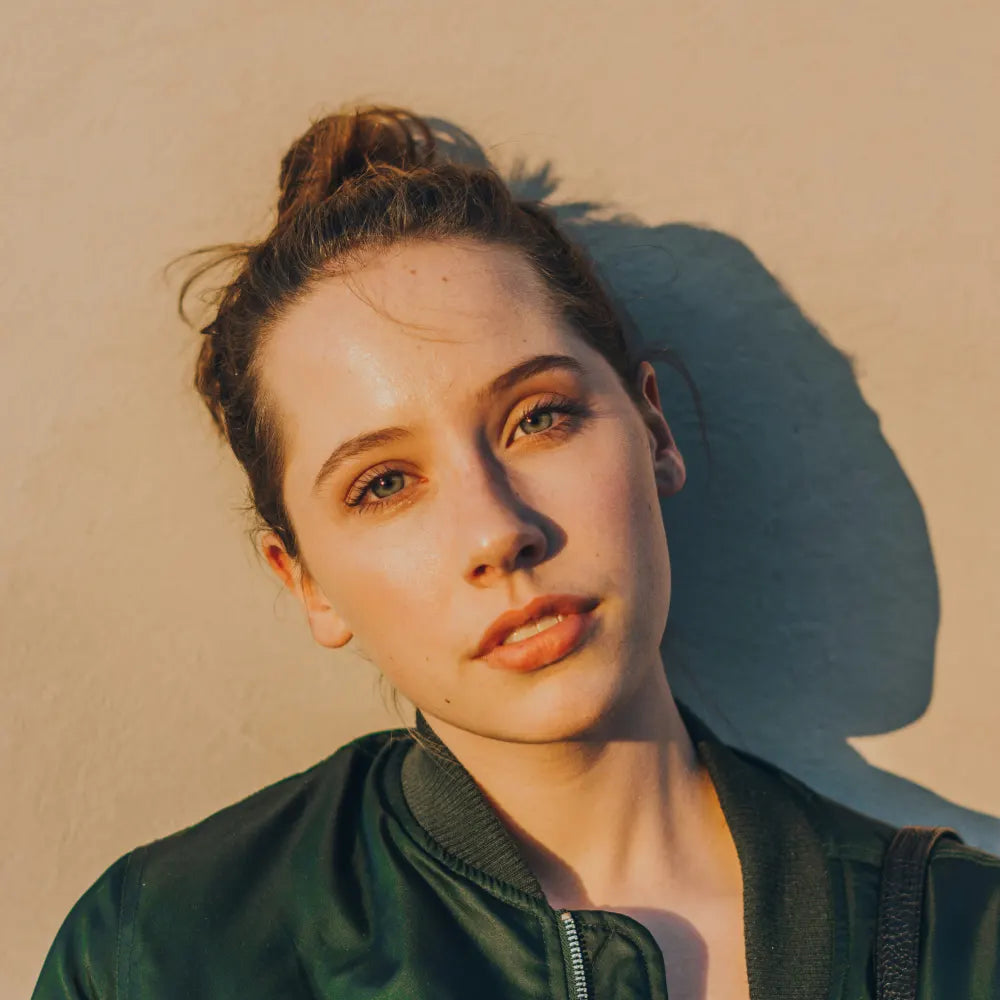 Woman with a green jacket against a beige background. Image credit: Haley Lawrence