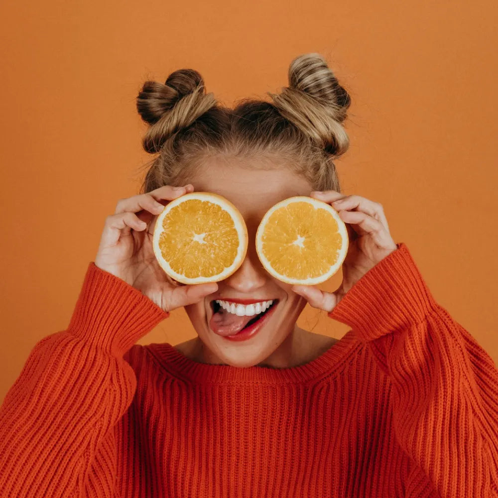 Model wearing an orange sweater and holding orange slices over her eyes - image by Noah Buscher