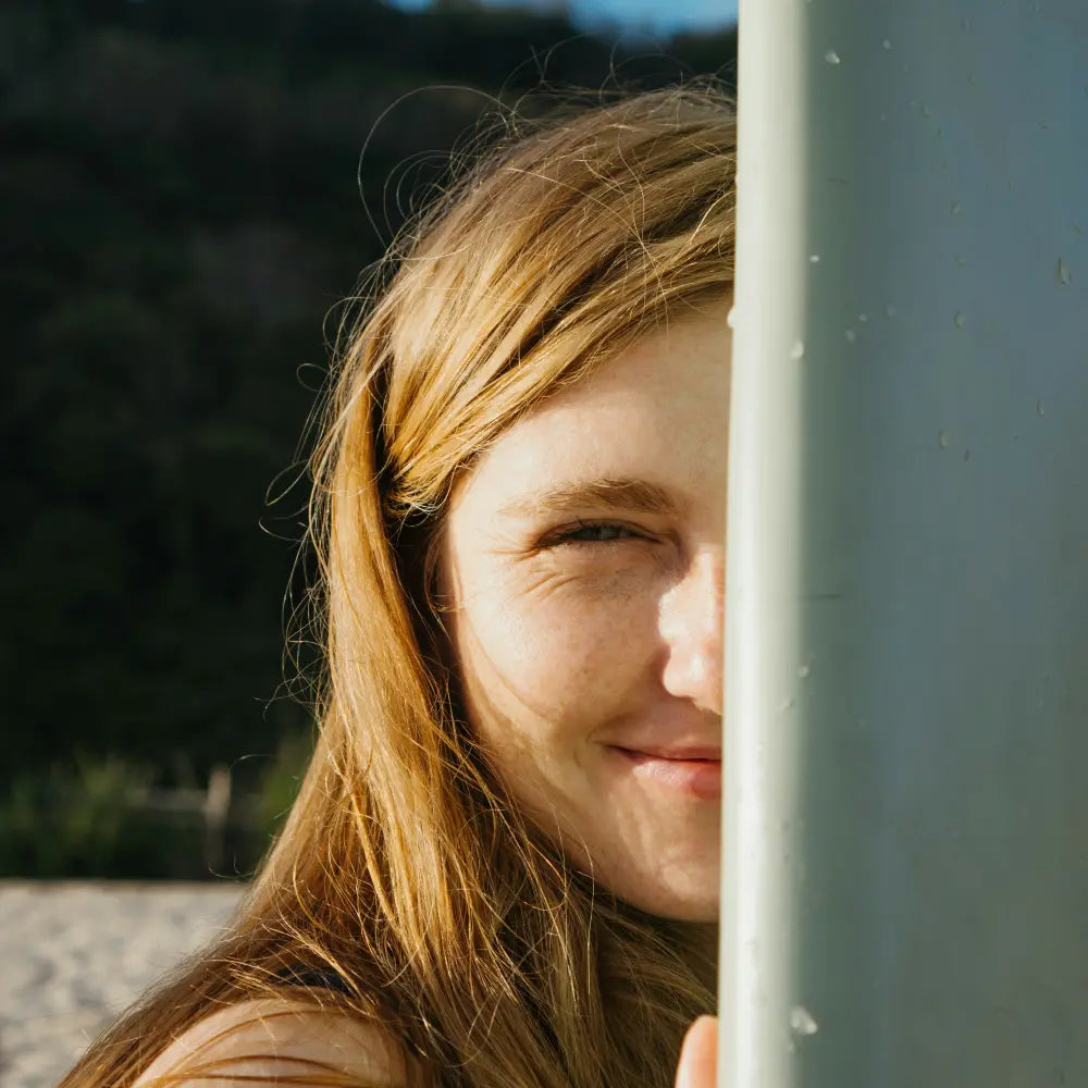 Woman peeking around a corner with a smile. Image credit: Polina Kuzovkova