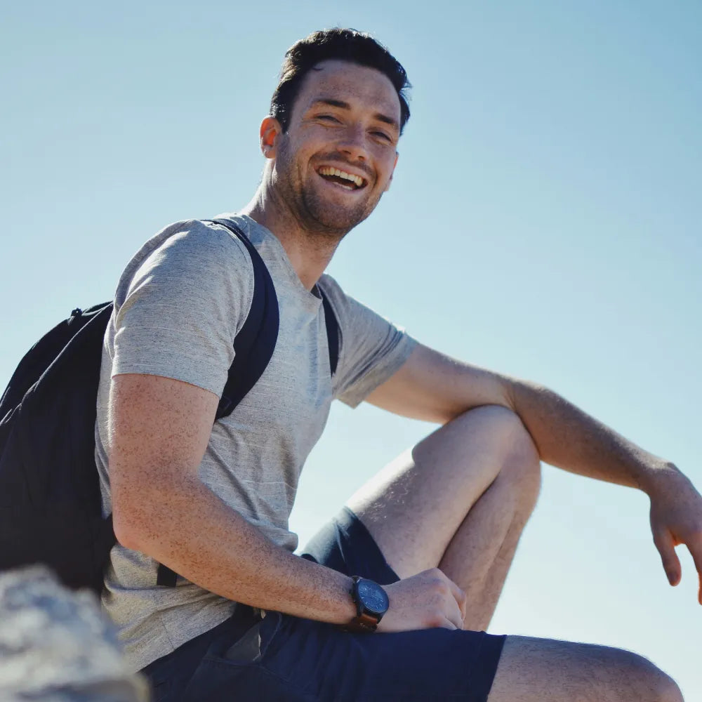 Man with a backpack sitting outdoors on a clear day. Photo credit: Stephanie Tuohy
