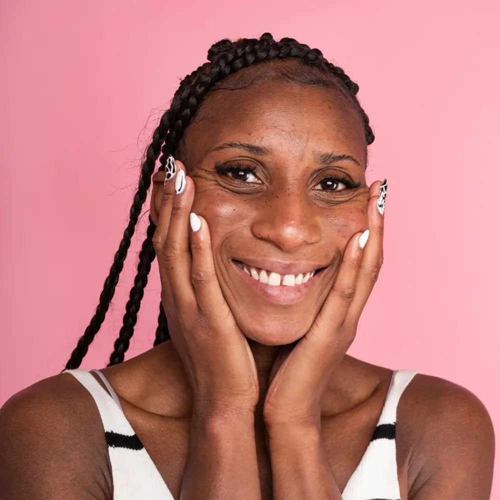 Woman with braided hair smiling against a pink background. Photo credit: Fanny Beckman