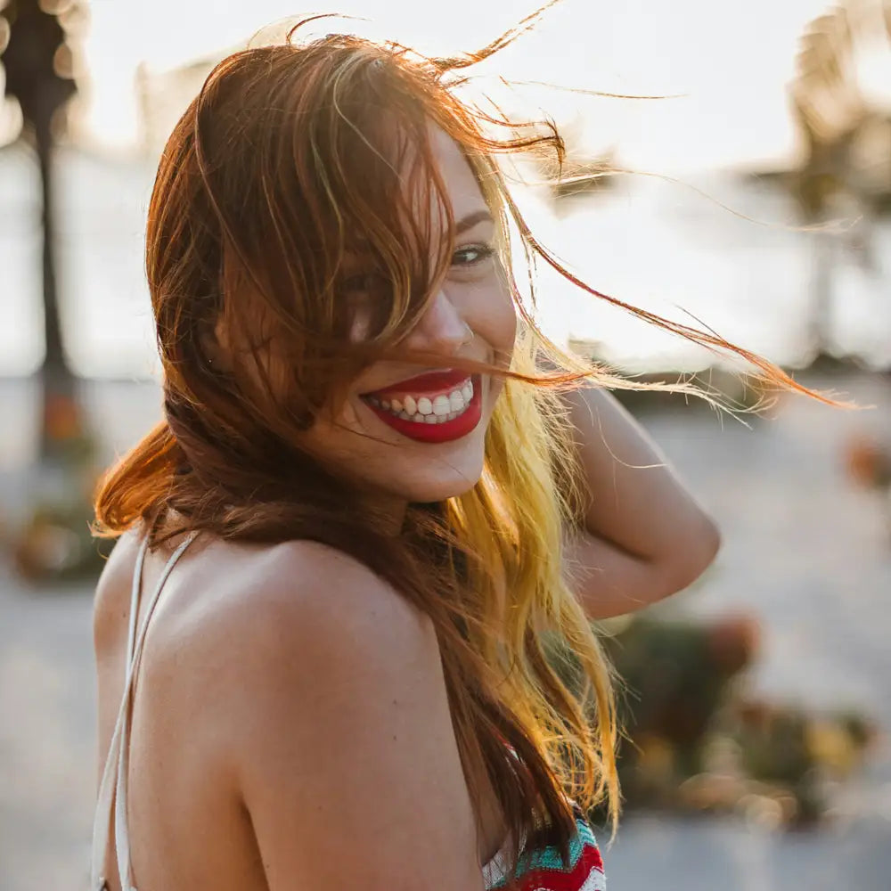 Woman with red hair and red lipstick smiling outdoors. Photo credit: Nelson Rodz