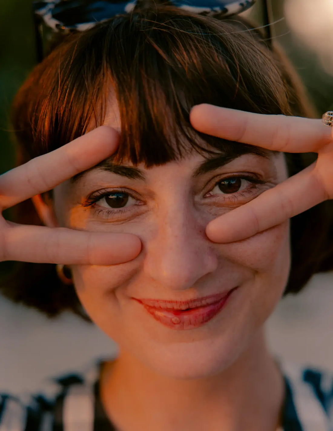 Person making a peace sign with their fingers in front of their eyes. Image credit: Michael T