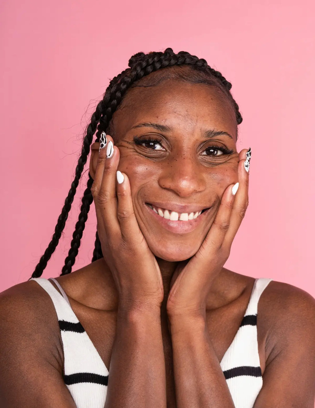 Woman with braided hair smiling against a pink background. Image credit: Fanny Beckman