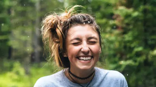 Happy person in woods during rain smiling. Photo credit: Jamie Brown