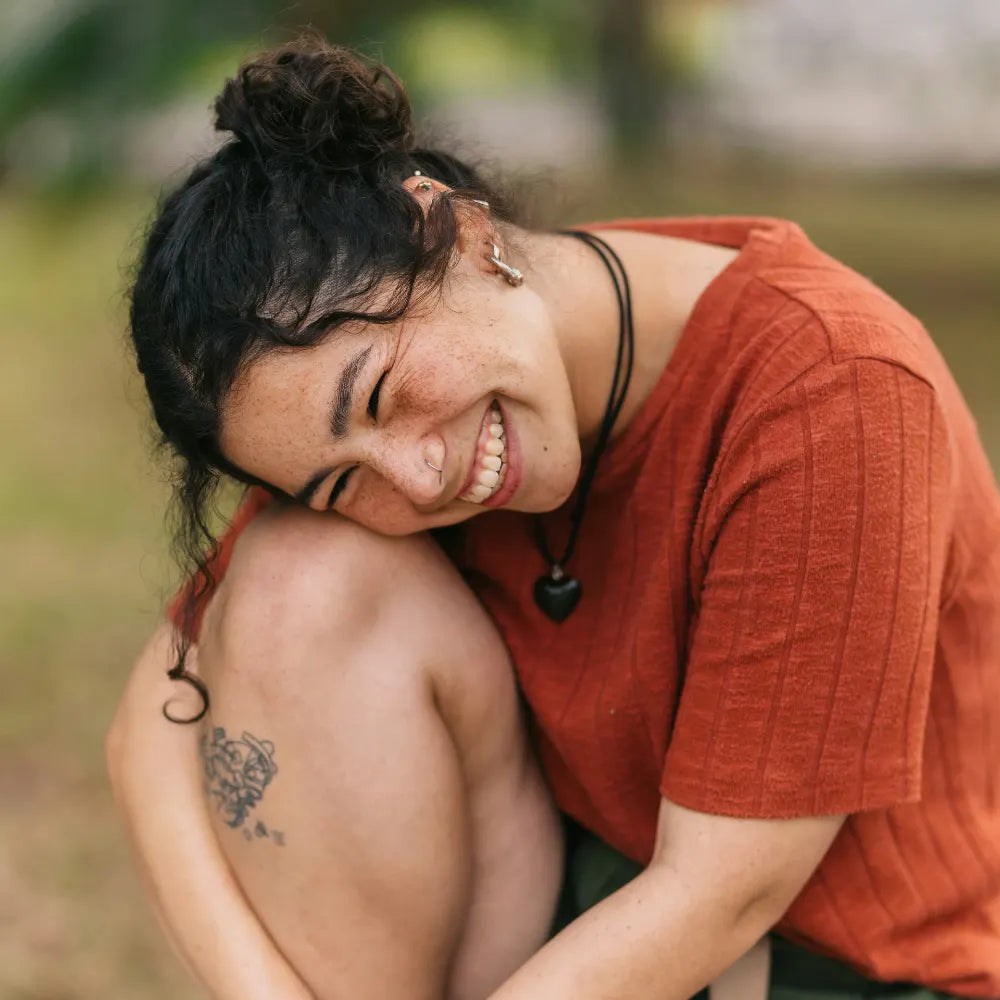 Young person laughing holding knee wearing orange shirt. Photo credit: Jordan Gonzalez